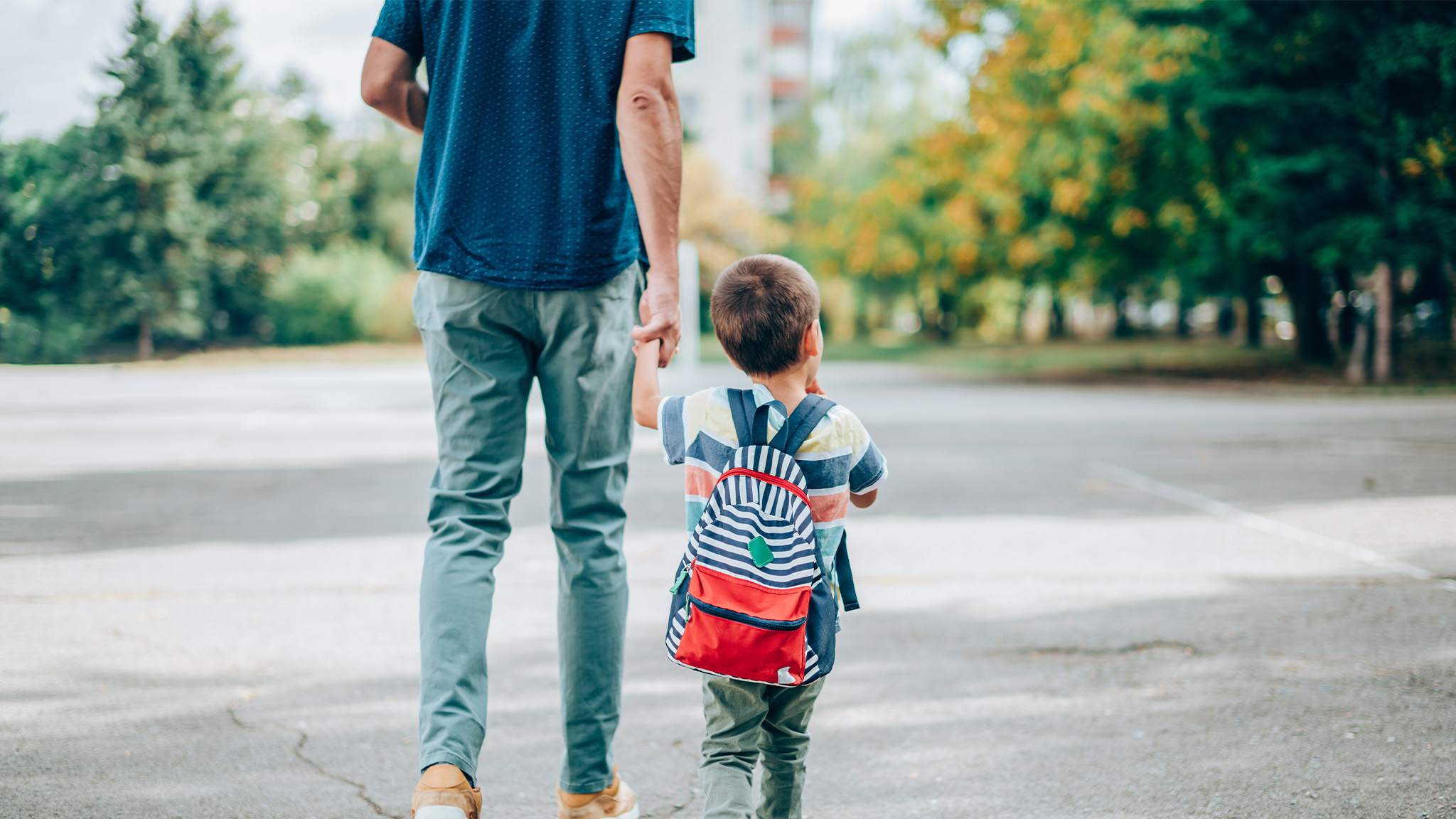 Father holds child’s hand while walking