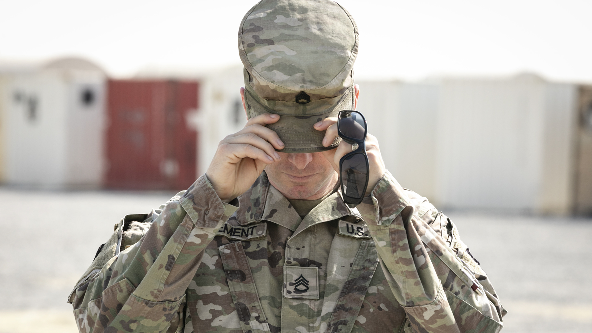 Service member adjusting cap with sunglasses
