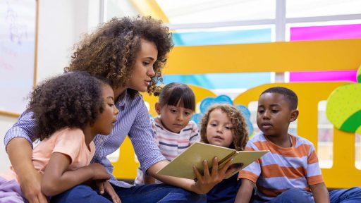 Teacher reading a book to a group of children