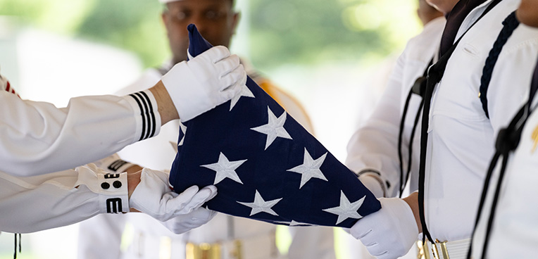 Sailors present folded American flag