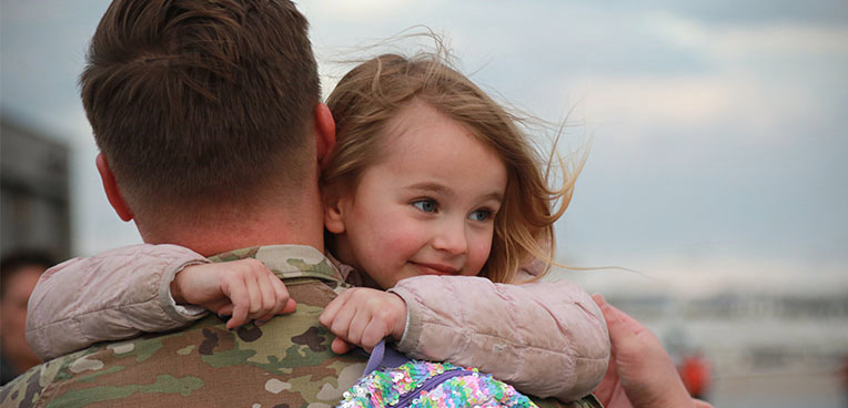 service member holding daughter