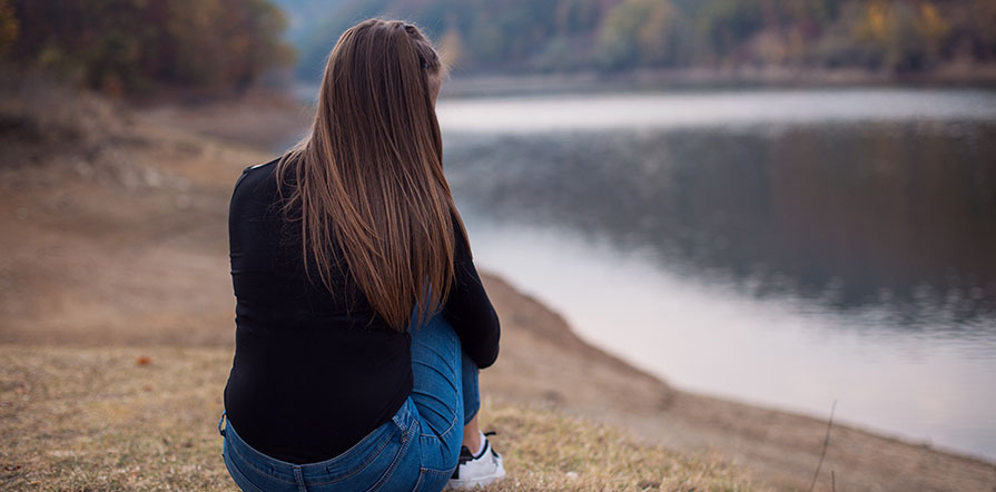 Woman sitting by lake