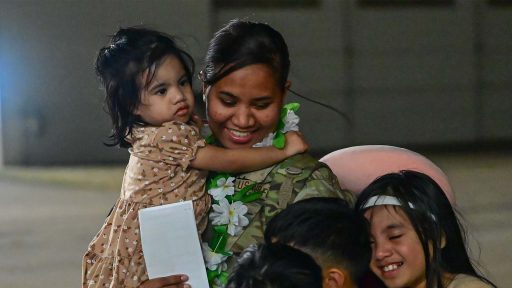 Service member hugging children