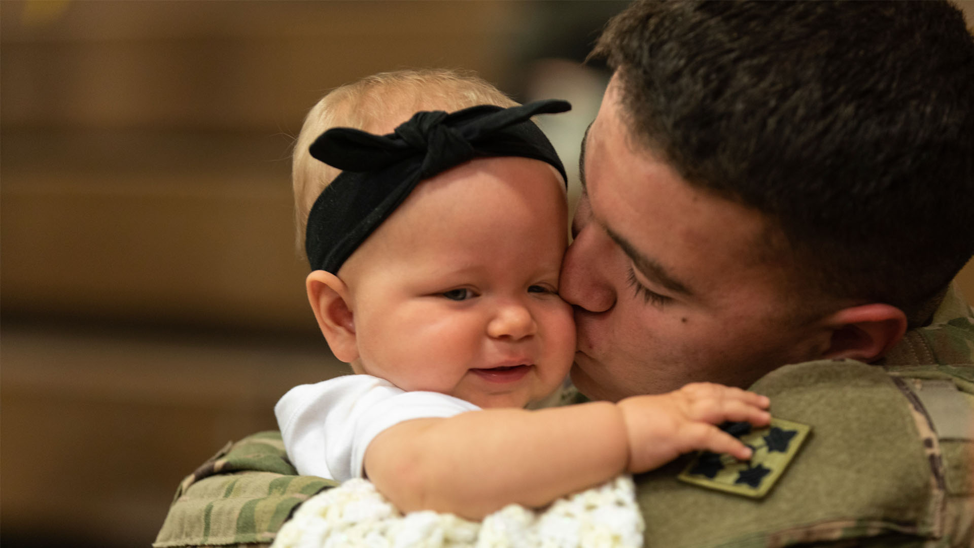 Service member holding and kissing a baby