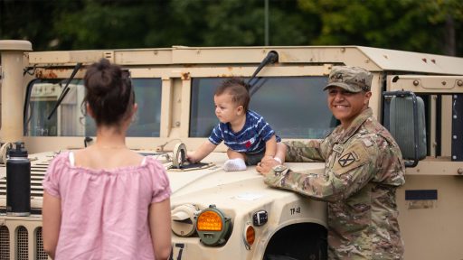 Service member holding infant on a hummer