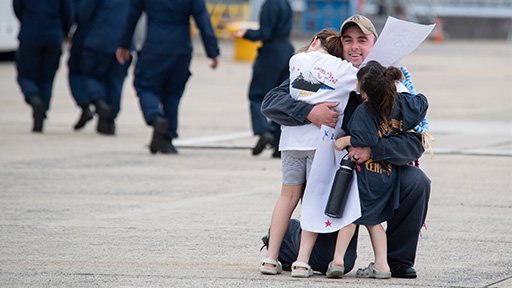 Service member hugging children