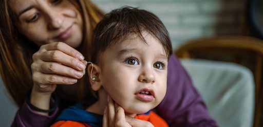 woman putting hearing aid in sons ear