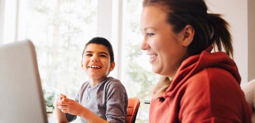 mom on computer beside special needs child