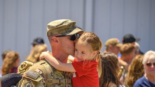 Service member holding and kissing daughter