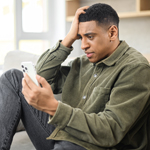 Sad young man holding smartphone