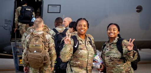 service members deploying smiling and showing peace sign