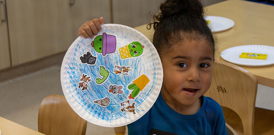 child holds up artwork