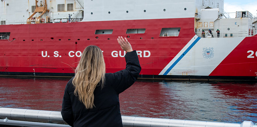 woman waves at Coast Guard ship