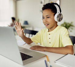 child on laptop waving and smiling