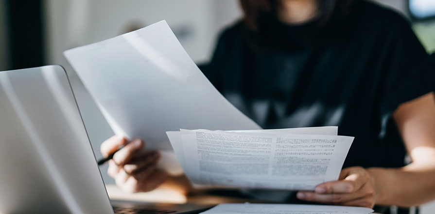 woman with paperwork at computer